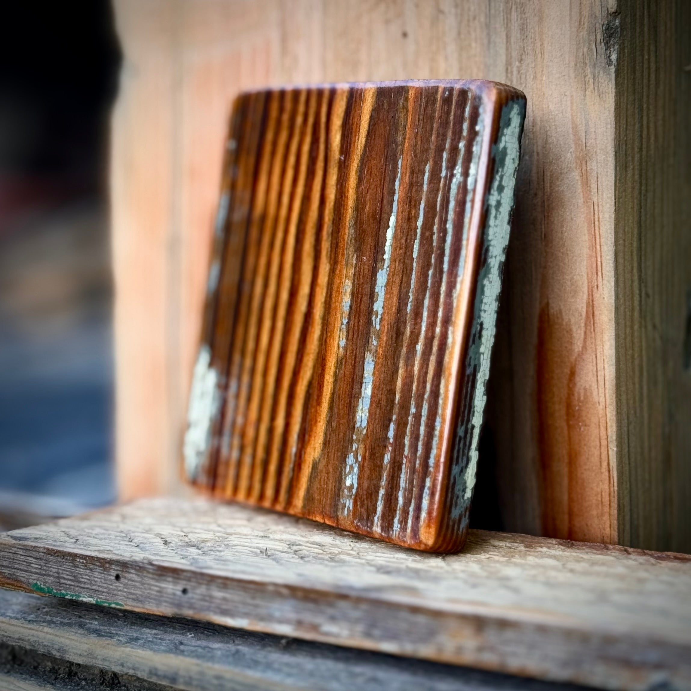 Heart pine coaster standing against old wood showing sealed paint and grain
