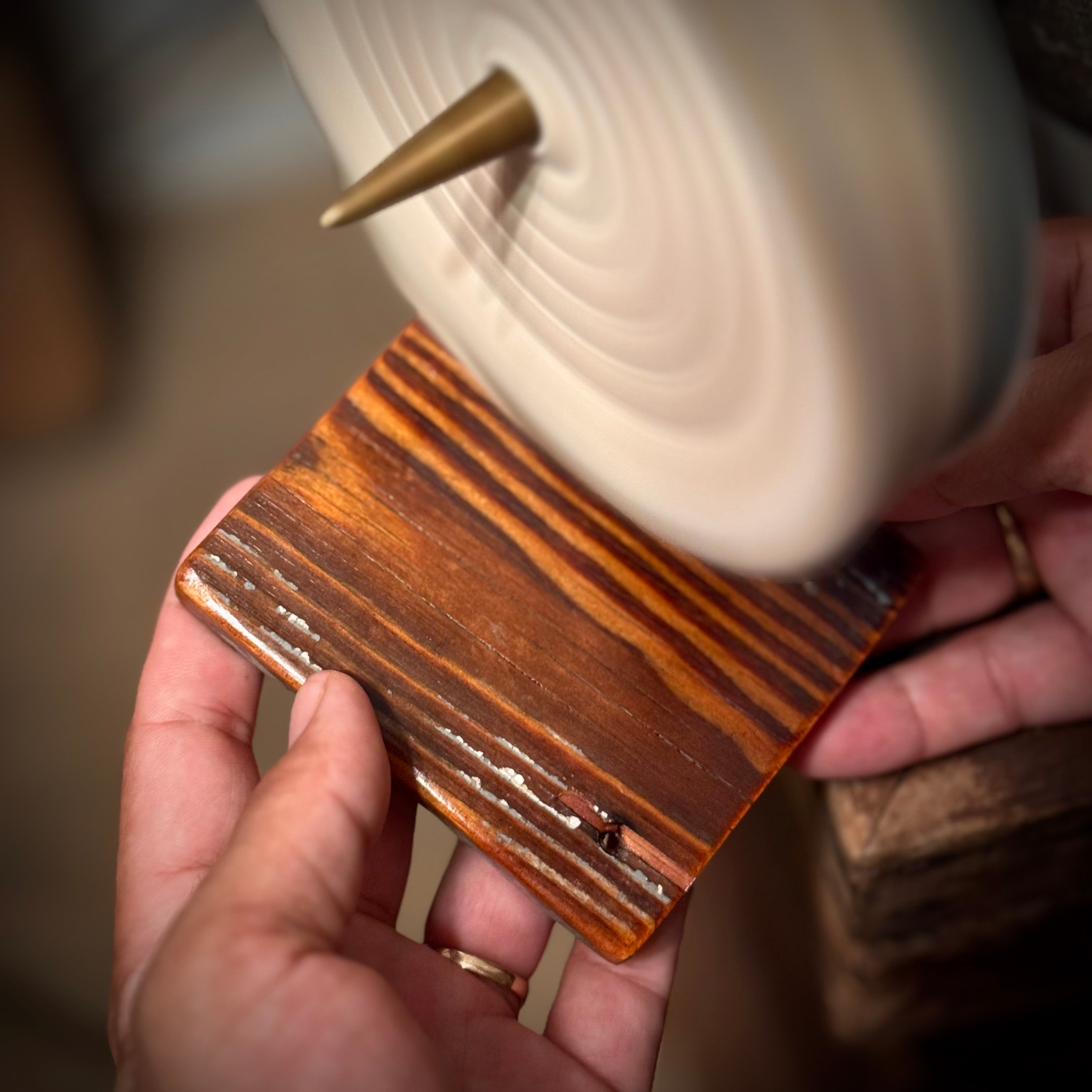 Close view of a single handmade heart pine coaster being polished by hand